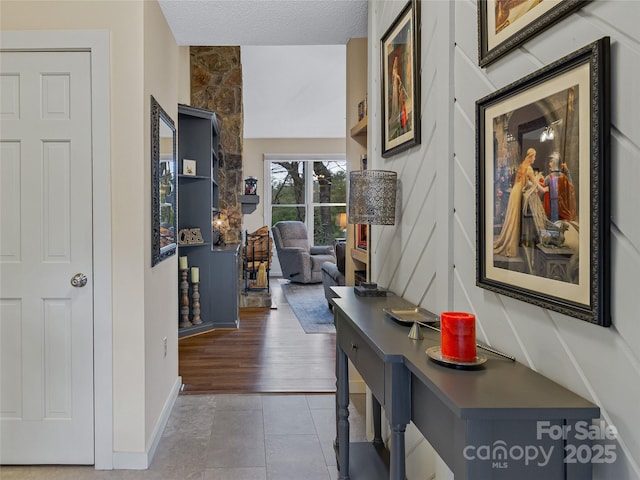 corridor featuring tile patterned floors, a textured ceiling, and baseboards