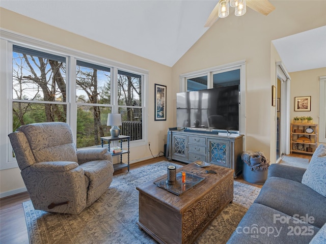 living area with baseboards, high vaulted ceiling, a ceiling fan, and wood finished floors