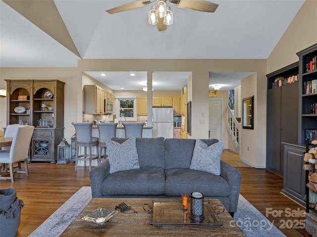 living area featuring stairway, a ceiling fan, wood finished floors, baseboards, and lofted ceiling