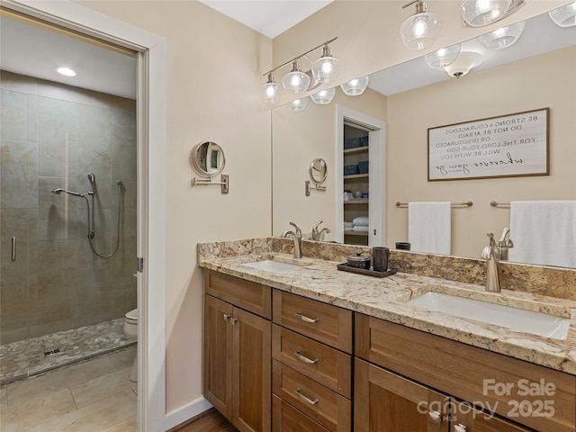 full bath featuring a sink, toilet, a stall shower, and double vanity