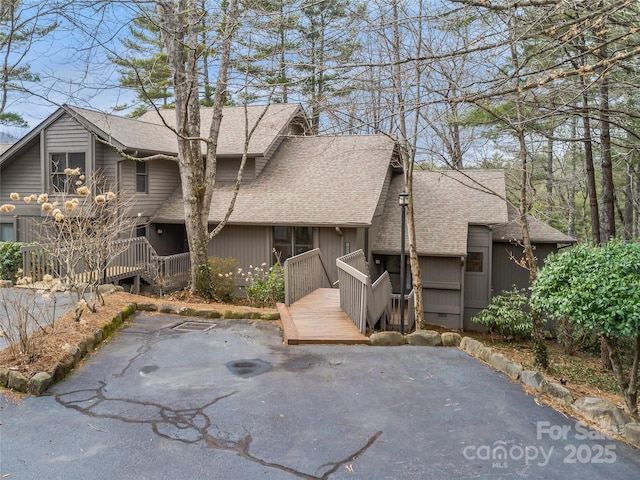 view of front of property with a wooden deck, a patio, and a shingled roof