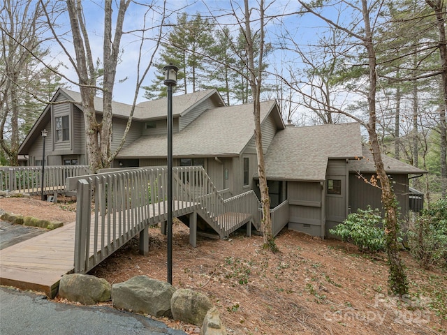 view of property exterior featuring crawl space, a deck, and a shingled roof