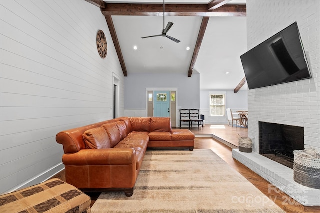 living room featuring high vaulted ceiling, a fireplace, wood finished floors, and beam ceiling