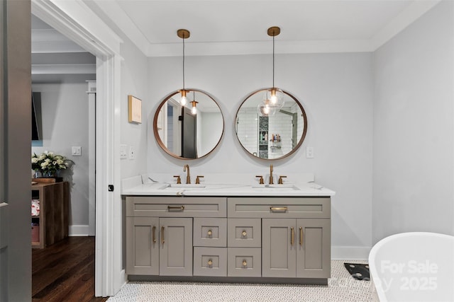 full bath featuring baseboards, a sink, a freestanding bath, and double vanity