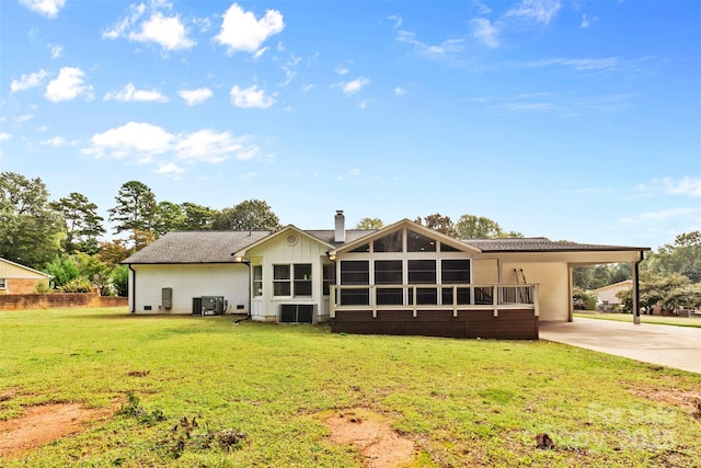 rear view of house with an attached carport, central AC, driveway, a lawn, and a chimney