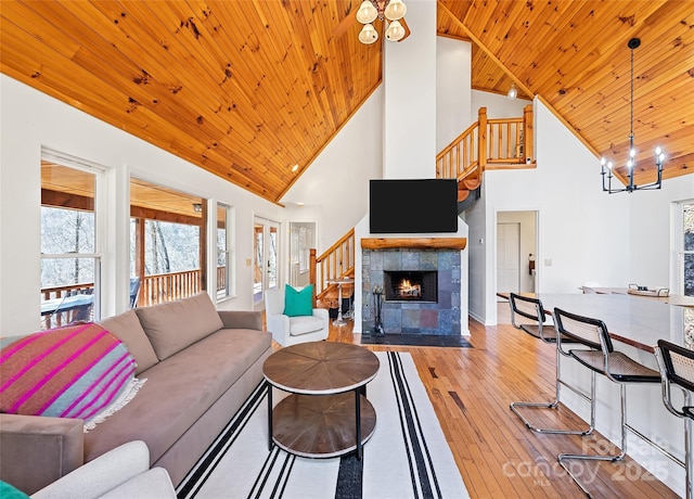 living area featuring a fireplace, stairway, a chandelier, wooden ceiling, and hardwood / wood-style floors