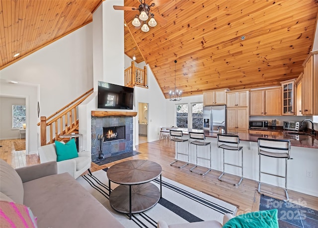 living area with a fireplace, light wood-style flooring, wood ceiling, baseboards, and stairs