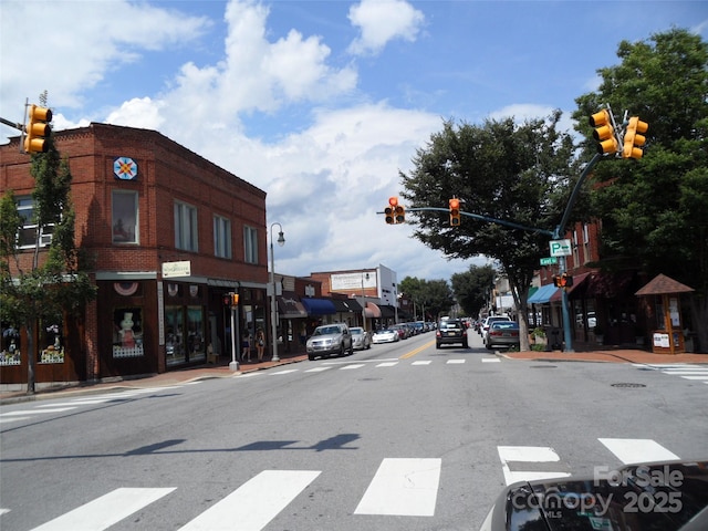 view of road with traffic lights, street lights, traffic signs, sidewalks, and curbs