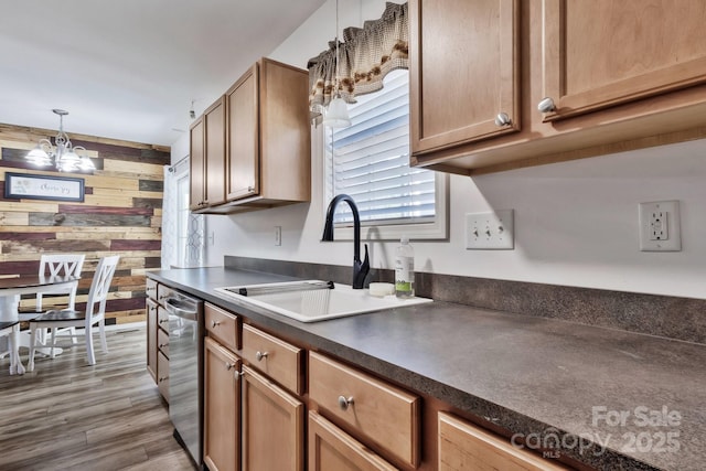 kitchen featuring dishwasher, dark countertops, wood finished floors, wood walls, and a sink