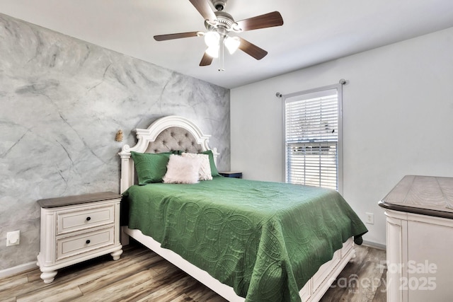 bedroom with a ceiling fan, baseboards, and wood finished floors