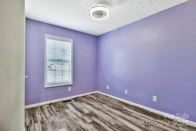 unfurnished room with baseboards and wood finished floors