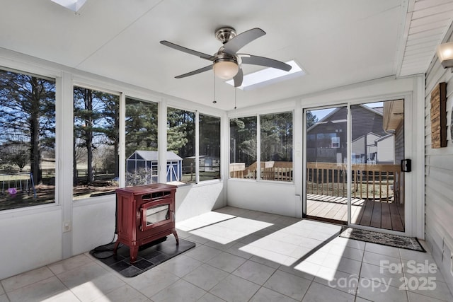 sunroom / solarium with plenty of natural light, a wood stove, and ceiling fan