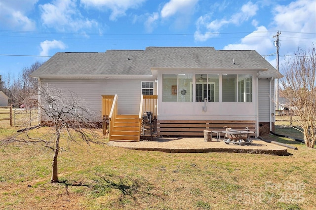 back of house featuring a sunroom, a shingled roof, fence, and a lawn