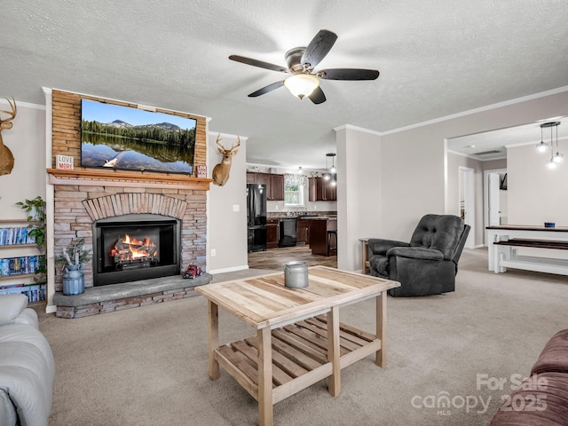 living area with a textured ceiling, ceiling fan, light colored carpet, a large fireplace, and crown molding