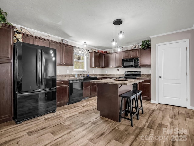 kitchen with dark brown cabinetry, light wood finished floors, a breakfast bar, a textured ceiling, and black appliances