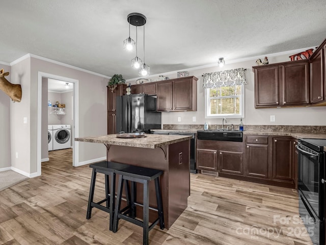 kitchen with a kitchen island, light wood-style floors, independent washer and dryer, and black appliances