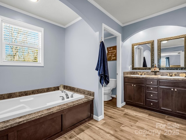 full bath featuring double vanity, toilet, ornamental molding, wood finished floors, and a garden tub