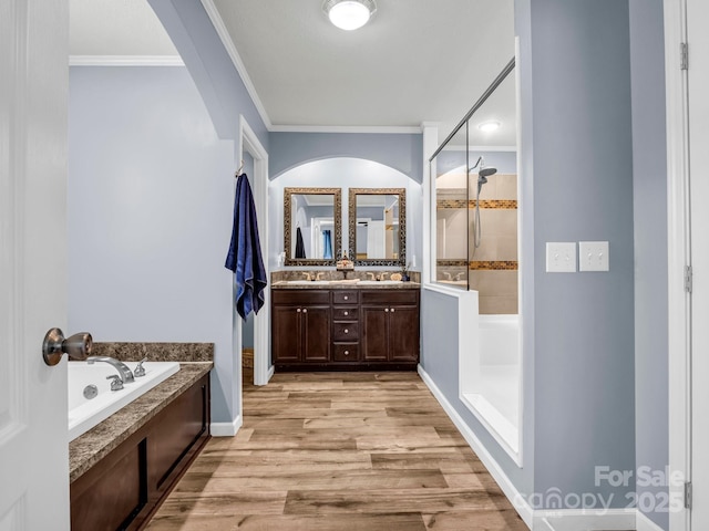 full bathroom featuring a sink, wood finished floors, a tile shower, a bath, and double vanity