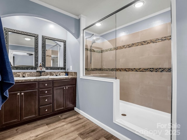 full bathroom featuring wood finished floors, crown molding, a sink, and walk in shower