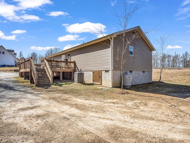 view of side of property featuring stairway, a deck, and central AC