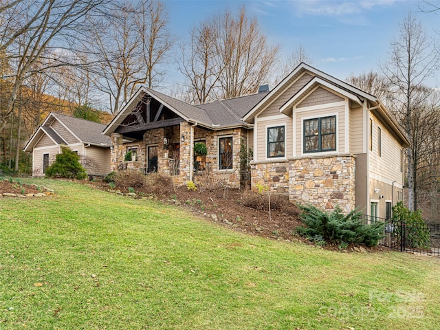 craftsman house with a front yard, stone siding, fence, and a chimney