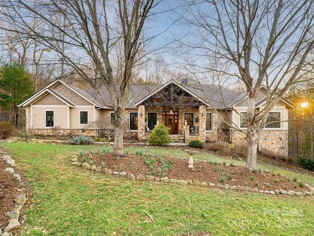 craftsman inspired home featuring stone siding, a front lawn, and covered porch