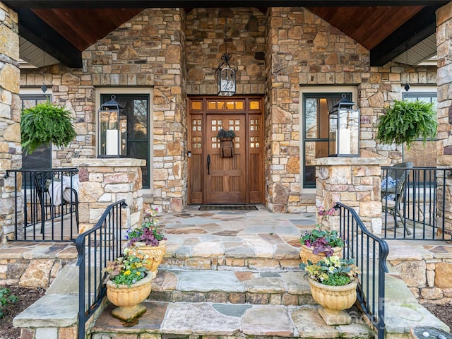 entrance to property featuring stone siding and covered porch