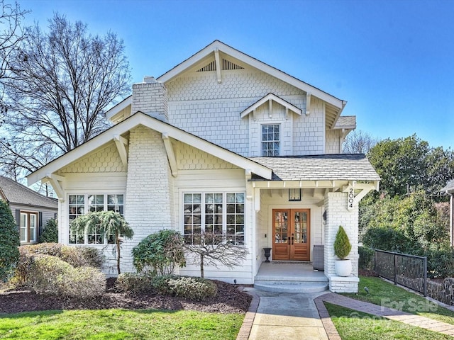 craftsman-style home with a chimney, fence, and french doors