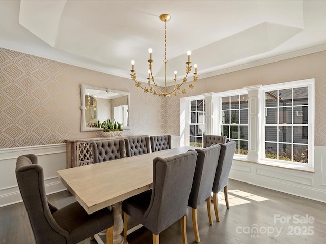 dining area with a decorative wall, a wainscoted wall, wood finished floors, a raised ceiling, and wallpapered walls