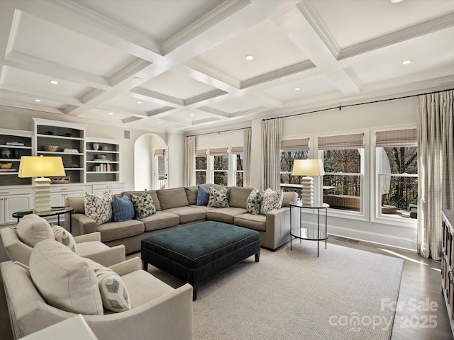 living area featuring arched walkways, coffered ceiling, wood finished floors, visible vents, and beam ceiling