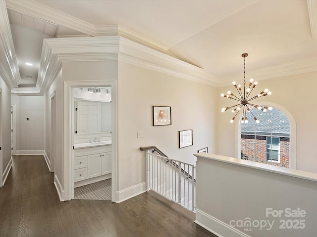 hall with ornamental molding, dark wood-type flooring, a sink, and an upstairs landing