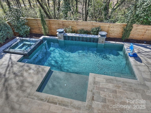 view of pool featuring a fenced backyard and a pool with connected hot tub