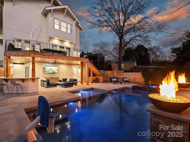 view of pool featuring a patio, stairs, outdoor dry bar, a fenced in pool, and an outdoor living space with a fire pit