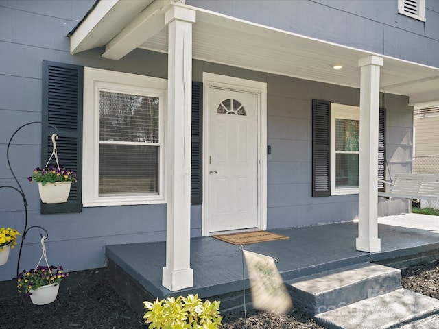 view of exterior entry with covered porch and visible vents