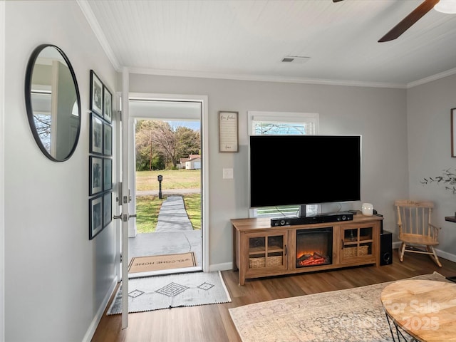 living area featuring baseboards, plenty of natural light, visible vents, and wood finished floors