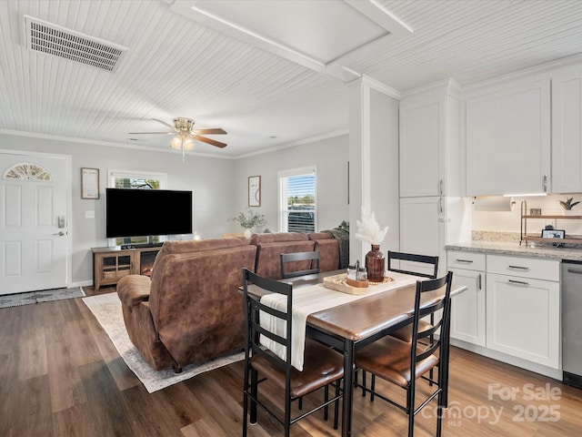 dining space featuring a ceiling fan, wood finished floors, visible vents, and crown molding