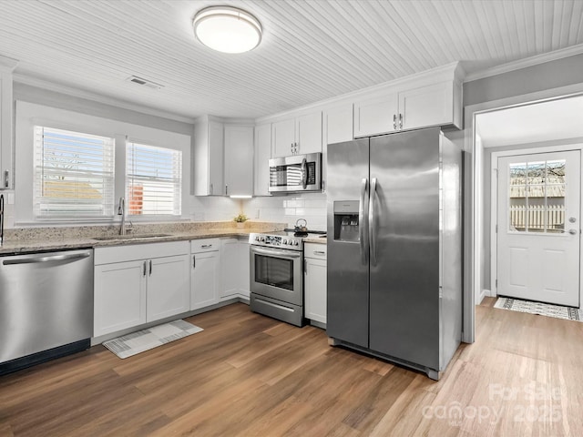 kitchen featuring crown molding, stainless steel appliances, visible vents, a sink, and light stone countertops