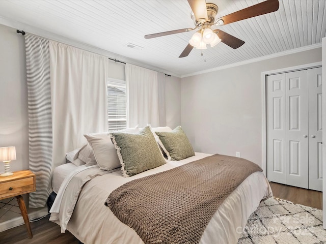 bedroom featuring ornamental molding, a closet, wood finished floors, and visible vents