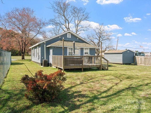 rear view of property featuring a lawn, fence, central AC, and a wooden deck