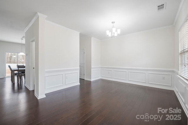 spare room with an inviting chandelier, visible vents, dark wood-style flooring, and ornamental molding