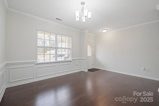 unfurnished room featuring visible vents, a chandelier, a wainscoted wall, ornamental molding, and dark wood-style floors