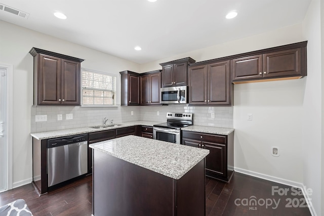 kitchen featuring a sink, dark wood-type flooring, dark brown cabinets, appliances with stainless steel finishes, and tasteful backsplash