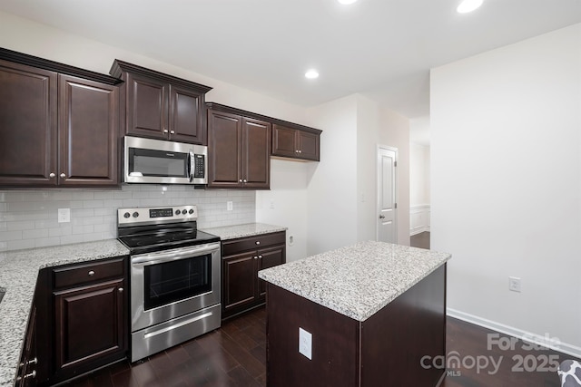 kitchen with a kitchen island, dark brown cabinetry, dark wood finished floors, decorative backsplash, and appliances with stainless steel finishes