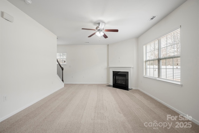 unfurnished living room with a wealth of natural light, a fireplace with flush hearth, baseboards, and carpet floors