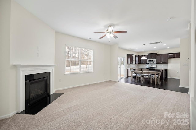 unfurnished living room with visible vents, a fireplace with flush hearth, a ceiling fan, recessed lighting, and baseboards