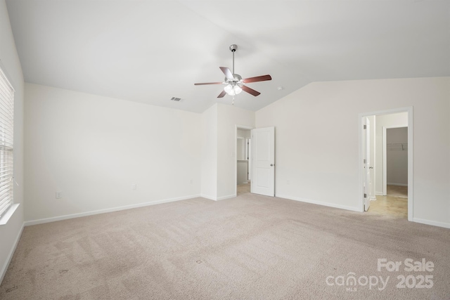 unfurnished bedroom with visible vents, vaulted ceiling, a spacious closet, a closet, and carpet flooring