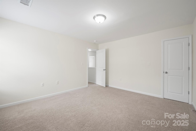 spare room featuring visible vents, baseboards, and light carpet