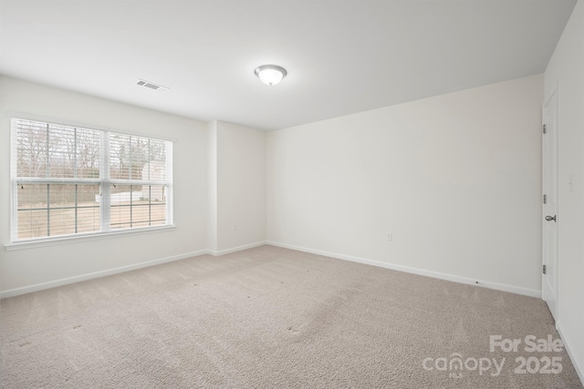 carpeted spare room featuring visible vents and baseboards