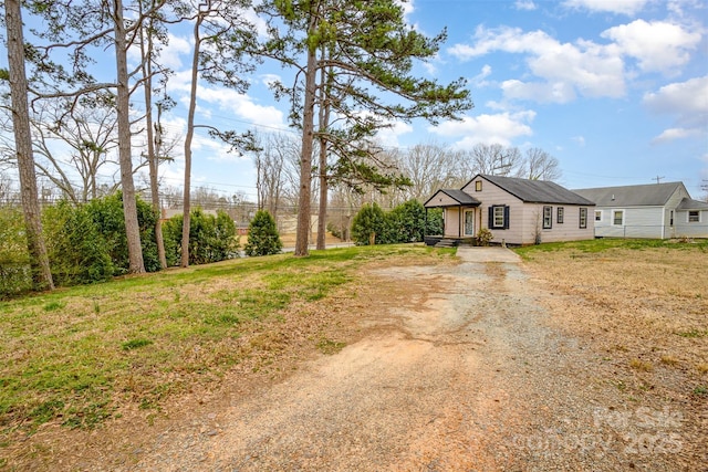 view of front of house with a front lawn and dirt driveway