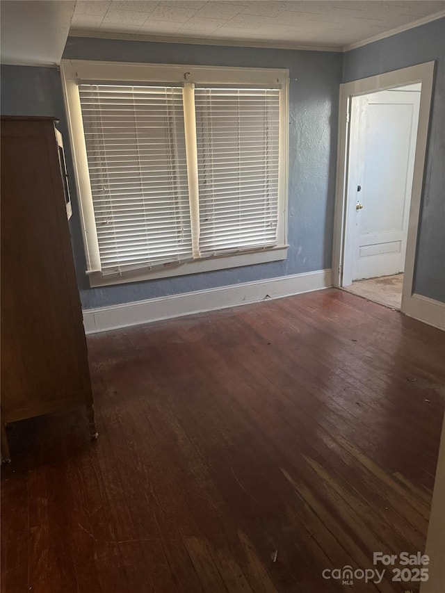 unfurnished room with crown molding, wood finished floors, and baseboards